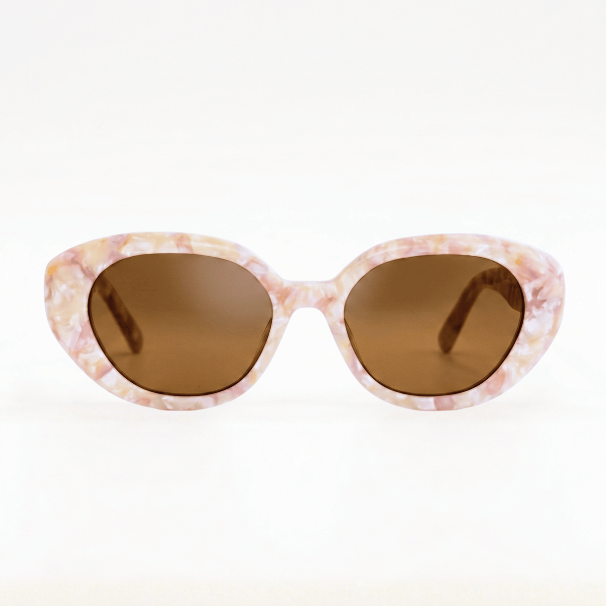 Lunettes de soleil de forme yeux de chat pour femme, monture en acétate effet nacre rose et beige pastel avec verres teintés bruns, vue de face.