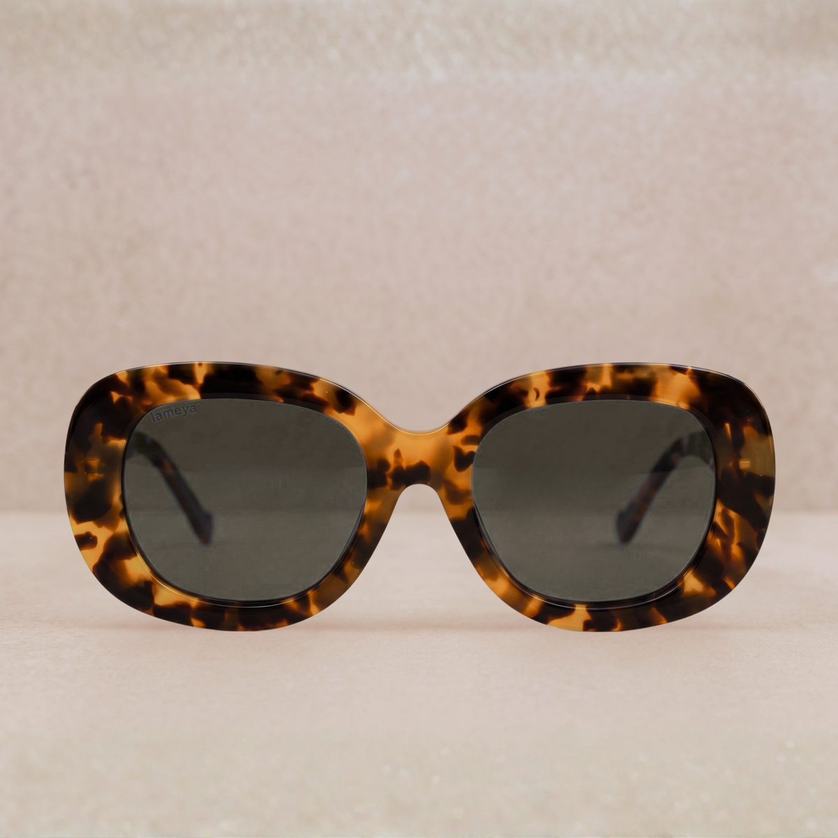 Lunettes de soleil pour femme style papillon, monture en acétate écaille de tortue et verres teintés gris.