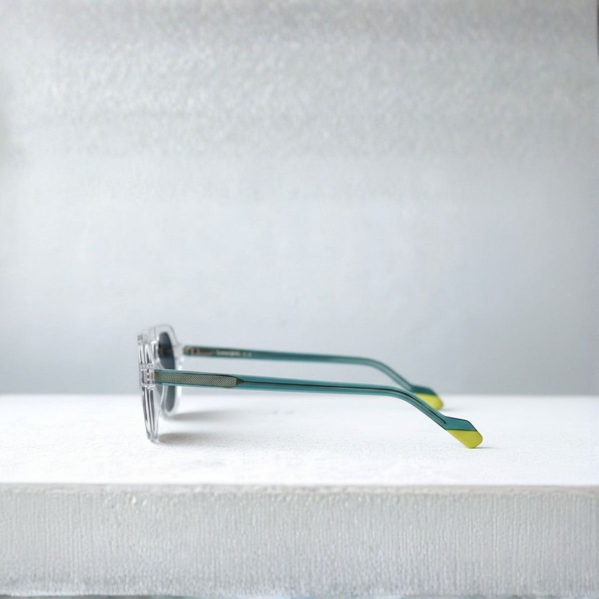  lunettes de soleil en acétate transparent, avec branches bleu canard translucides, armature métallique guillochée et embouts jaune fluo.