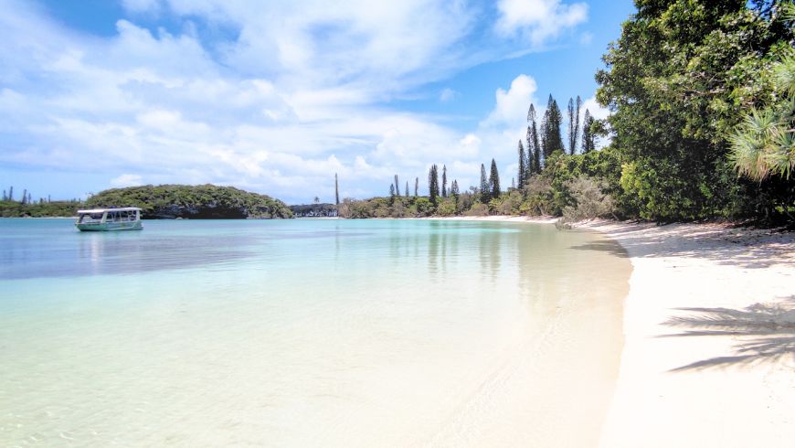 Vue d’une plage paradisiaque aux eaux cristallines (plage de Kanuméra) avec des reflets éblouissants à la surface de l'eau, illustrant l’effet de réverbération solaire sans l'utilisation de verres polarisés.